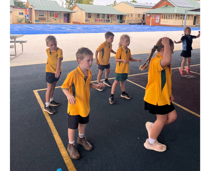 A group of students are outdoors, participating enthusiastically in performing arts activities, building creativity and self-expression through music, drama, and movement.