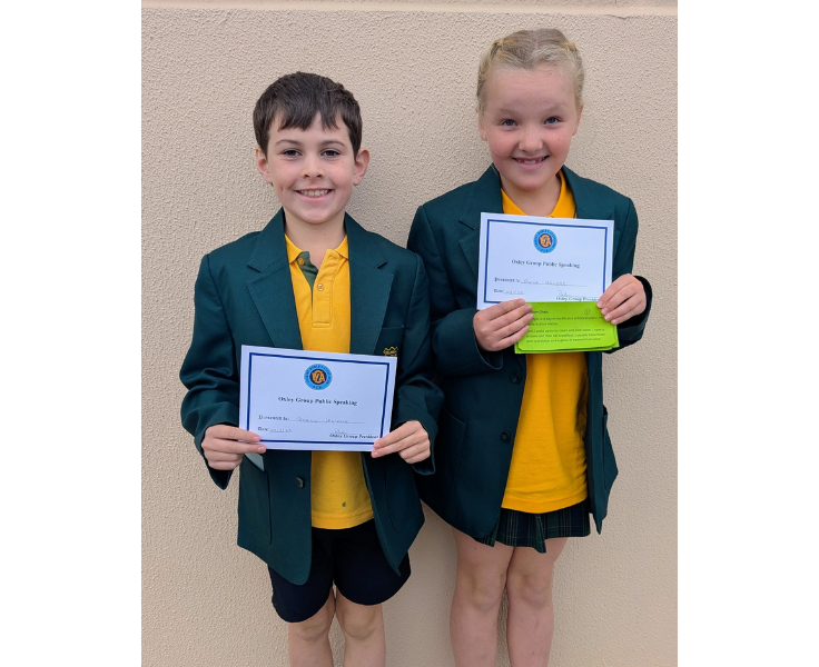 Two students proudly hold certificates, showcasing their achievements in debating and public speaking, where they develop communication, teamwork, and have opportunities to compete at local and state events.